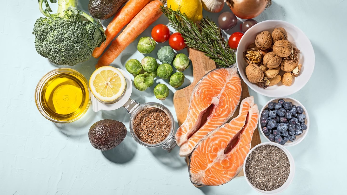 Flat lay of salmon, walnuts, blueberries, olive oil and fresh vegetables